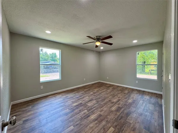 an empty room with wooden floor and windows