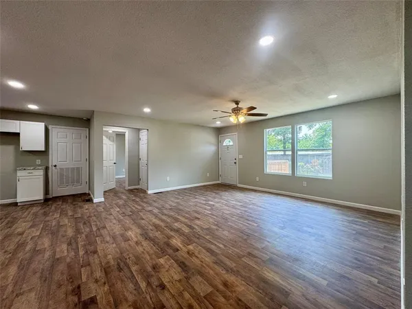 an empty room with wooden floor cabinet and windows