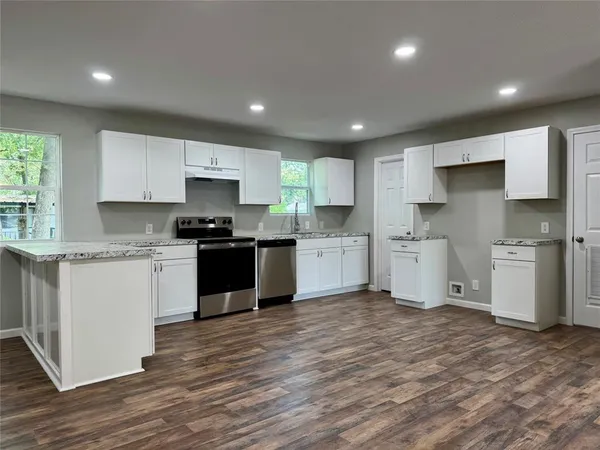a kitchen with granite countertop a sink cabinets and wooden floor