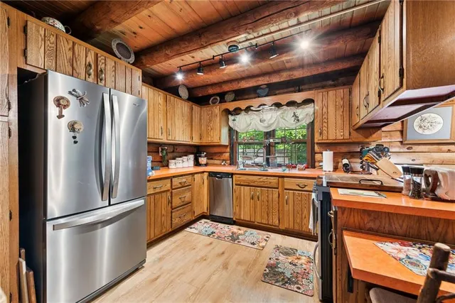 a kitchen with stainless steel appliances granite countertop a refrigerator a sink dishwasher a stove and white countertops with cabinets