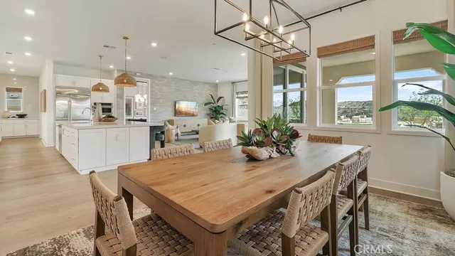 a view of a dining room and livingroom with furniture wooden floor a chandelier
