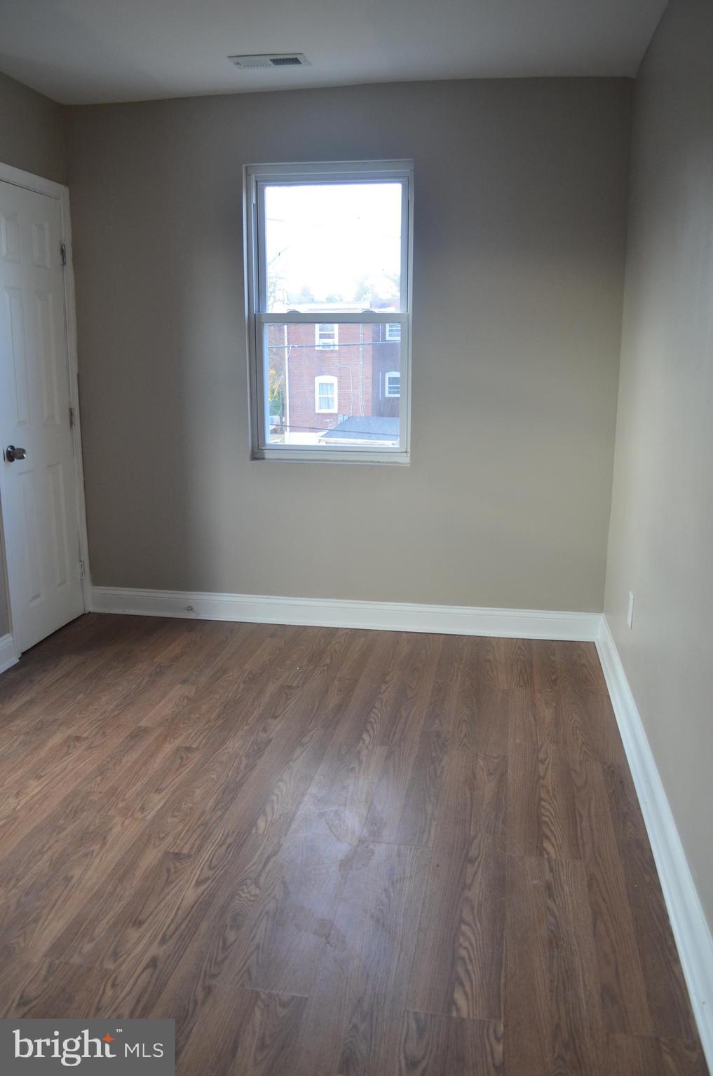 4952 Brookwood Road Baltimore, MD 21225 - Photo 4 of 13 an empty room with wooden floor and windows
