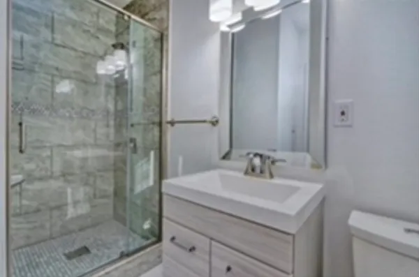 a bathroom with a shower sink vanity and mirror