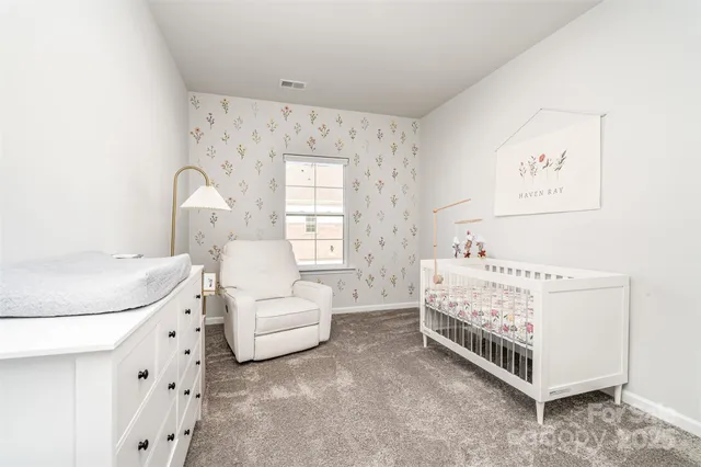 a white bed sitting in a bedroom next to a window with a dresser