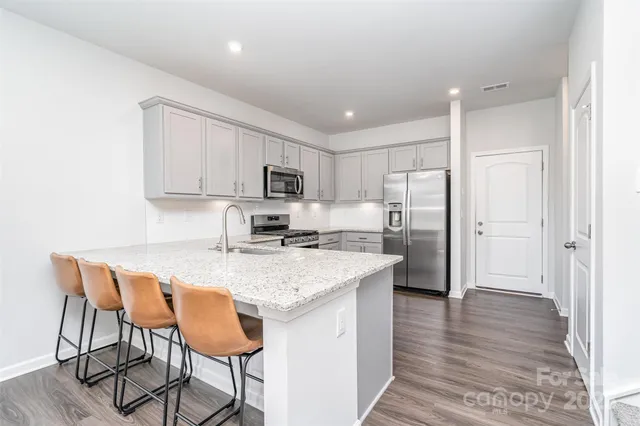a kitchen with stainless steel appliances granite countertop a table chairs sink refrigerator and cabinets