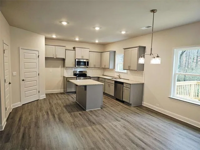 a kitchen with kitchen island a sink a stove a refrigerator and white cabinets with wooden floor