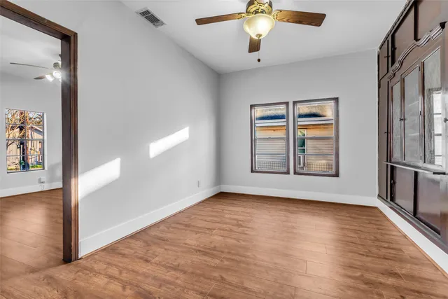 an empty room with wooden floor and windows