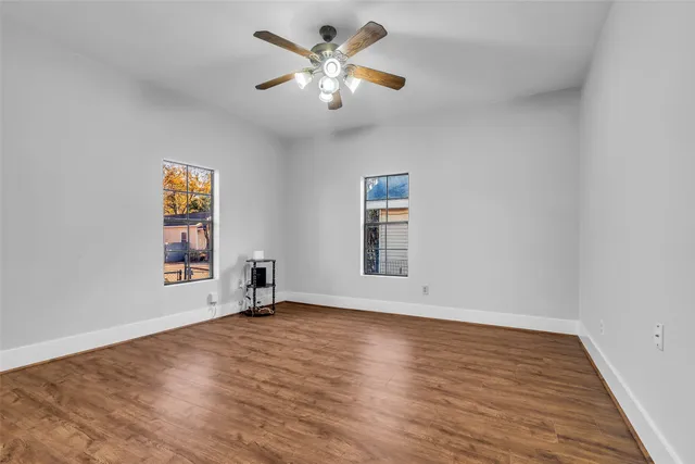 a view of an empty room with a window and wooden floor