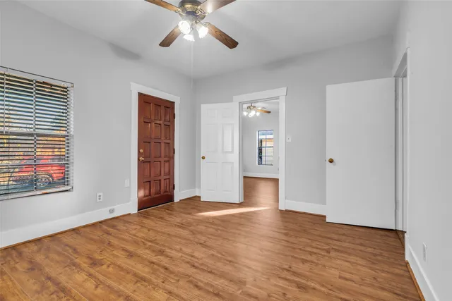 a view of an empty room with wooden floor and a window