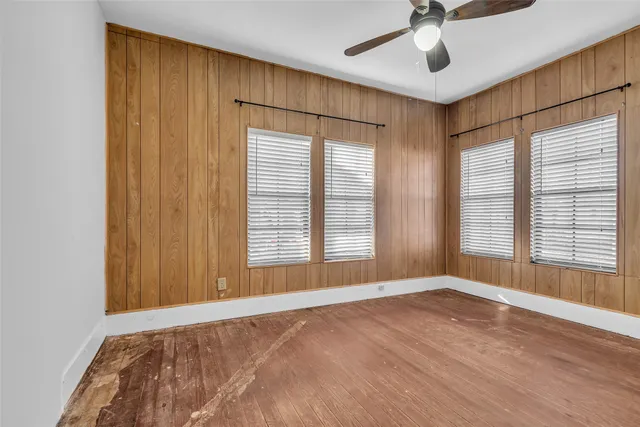 a view of an empty room with a window and hardwood floor