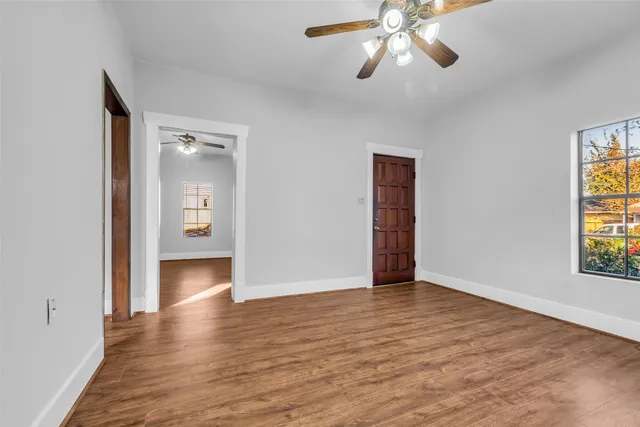 a view of an empty room with window and wooden floor