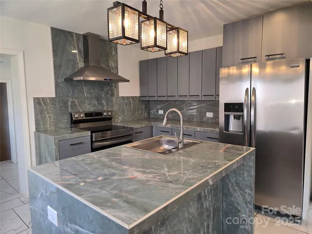 a kitchen with stainless steel appliances granite countertop a sink a stove and a refrigerator