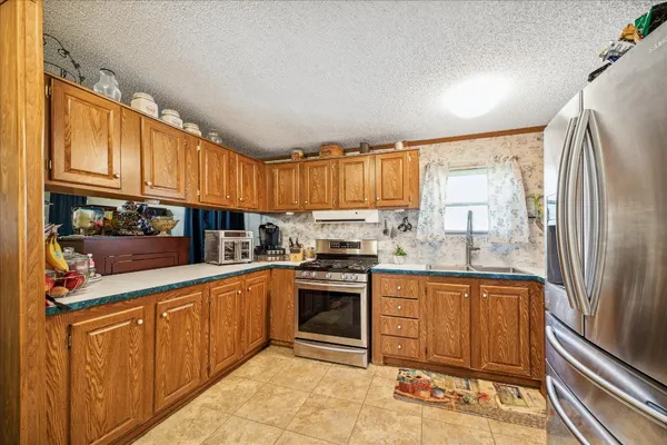 a kitchen with stainless steel appliances granite countertop a refrigerator a stove and a sink with cabinets