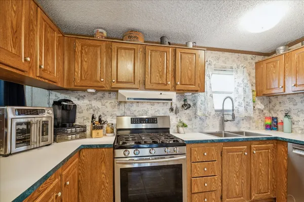 a kitchen with stainless steel appliances granite countertop a stove top oven a sink dishwasher and cabinets with wooden floor
