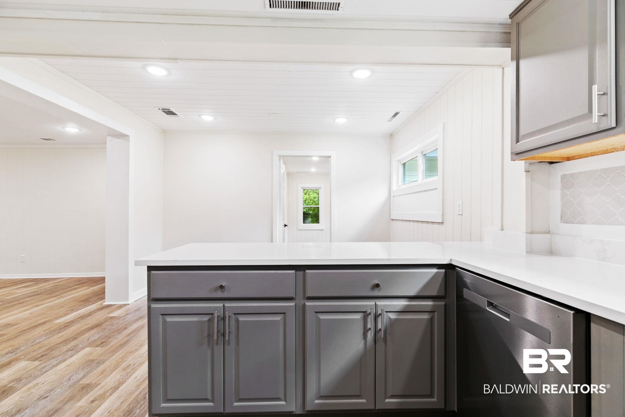 507 Byrne Street Bay Minette, AL 36507 - Photo 13 of 40 Kitchen featuring light hardwood / wood-style floors, gray cabinetry, kitchen peninsula, and stainless steel dishwasher