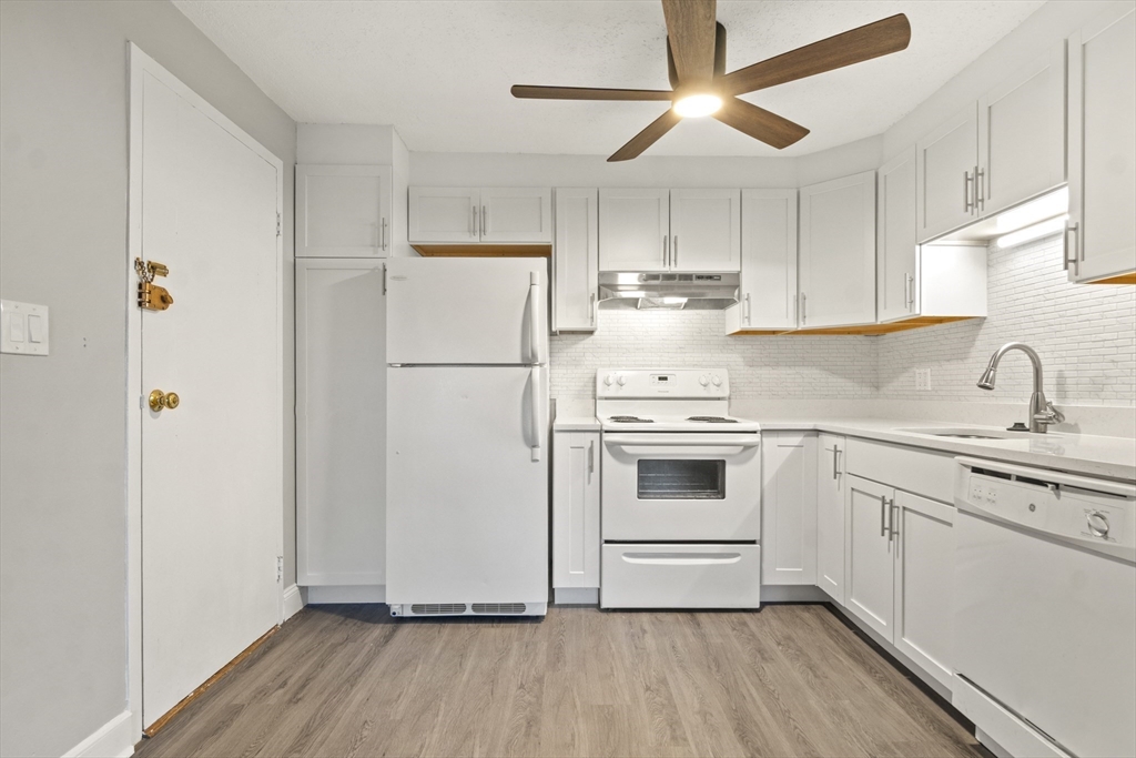 1105 Lexington Street, Unit 102 Waltham, MA 02452 - Photo 16 of 41 a kitchen with a refrigerator a sink and white cabinets