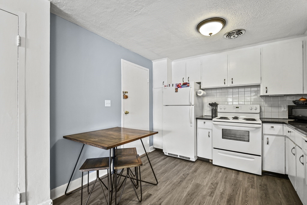1105 Lexington Street, Unit 102 Waltham, MA 02452 - Photo 20 of 41 a kitchen with a stove a refrigerator and white cabinets with wooden floor