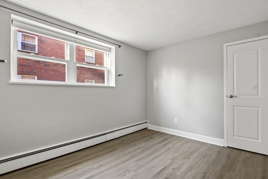 1105 Lexington Street, Unit 102 Waltham, MA 02452 - Photo 31 of 41 a view of an empty room with wooden floor and a window