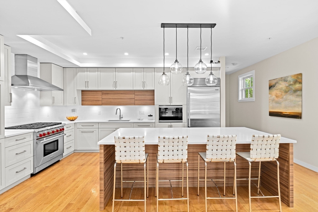 56-58 Perry Street, Unit 4 Brookline, MA 02446 - Photo 3 of 17 a kitchen with stainless steel appliances kitchen island granite countertop a stove and white cabinets