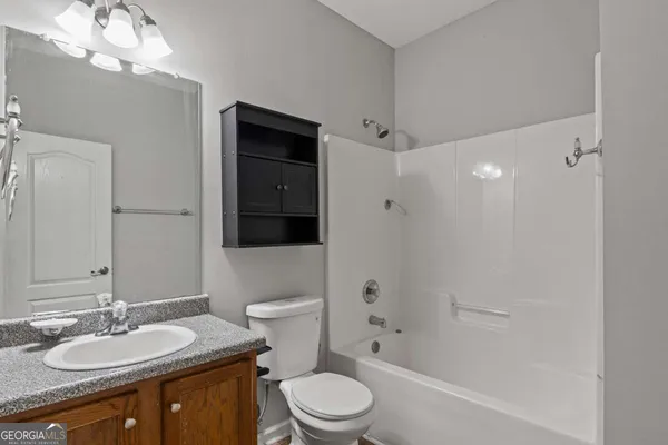 a bathroom with a granite countertop sink toilet a shower and a mirror