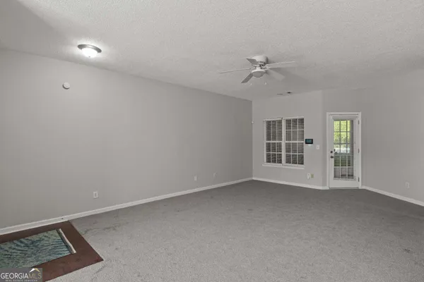 an empty room with chandelier fan and windows