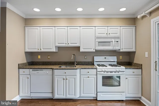 a kitchen with granite countertop a sink cabinets and stainless steel appliances