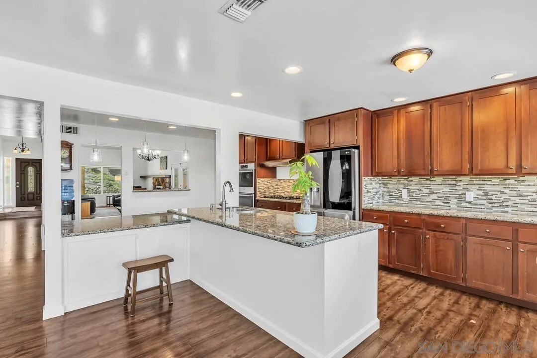 1509 Honey Hill Road El Cajon, CA 92020 - Photo 16 of 49 a kitchen with stainless steel appliances granite countertop wooden cabinets a stove a sink and a center island