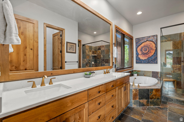 4892 Eagle Rdg Drive Eden, UT 84310 - Photo 22 of 39 Bathroom featuring a dual vanity with white countertops and gold-finish fixtures, a large soaking tub, and an enclosed shower with stone-tile surround