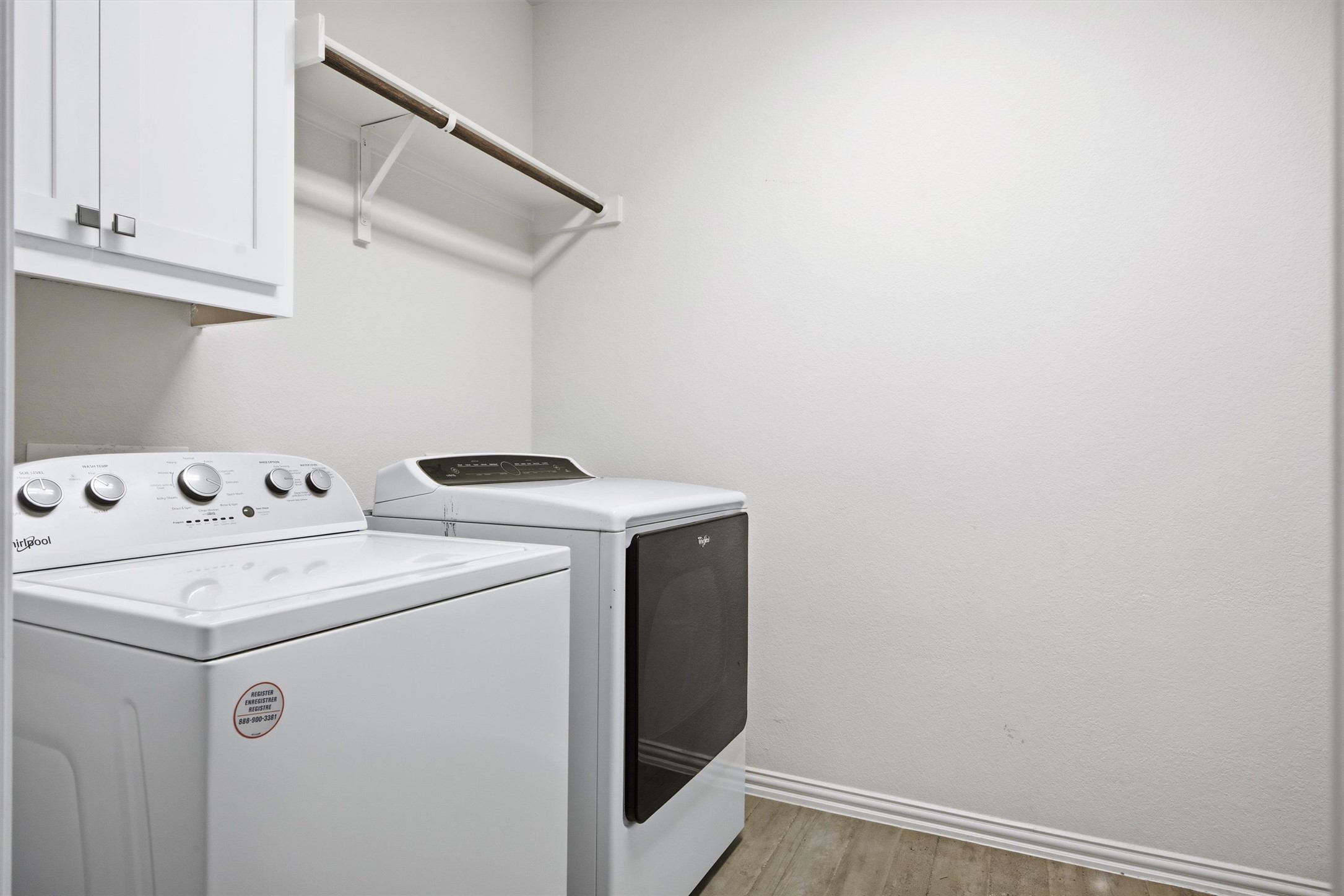 192 Raptor Beak Way Cedar Creek, TX 78612 - Photo 26 of 38 Dedicated laundry area featuring a white upper cabinet with brushed nickel hardware, a wall-mounted hanging rod, and wood-finish tile flooring
