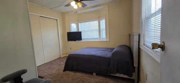 a bedroom with a bed and a flat tv screen on dresser