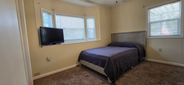 a bedroom with a bed and flat tv screen on the dresser
