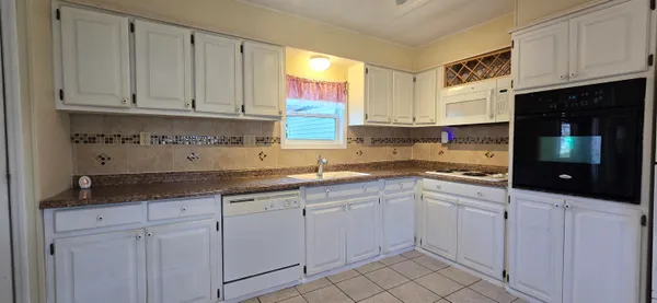 a kitchen with white cabinets and sink