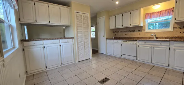 a kitchen with white cabinets a sink and dishwasher