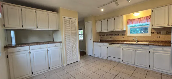 a kitchen with white cabinets a sink and a stove with wooden floor