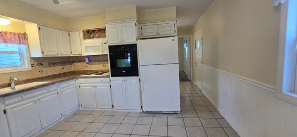 a kitchen with white cabinets a refrigerator and a sink