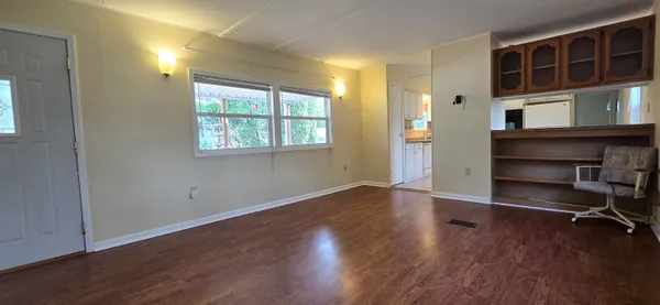 an empty room with wooden floor and windows