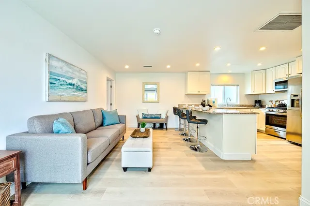 a kitchen with stainless steel appliances granite countertop a refrigerator a sink dishwasher a stove and white cabinets with wooden floor