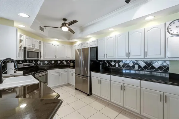a kitchen with white cabinets and sink