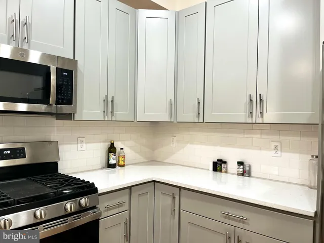 a kitchen with stainless steel appliances granite countertop white cabinets and a stove