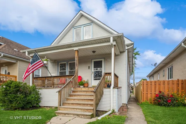 a view of a white house with a small yard plants and large tree