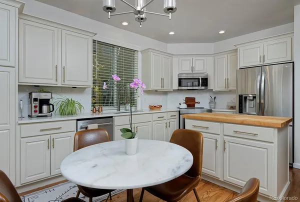 a kitchen with kitchen island granite countertop a sink a stove a refrigerator cabinets and a dining table