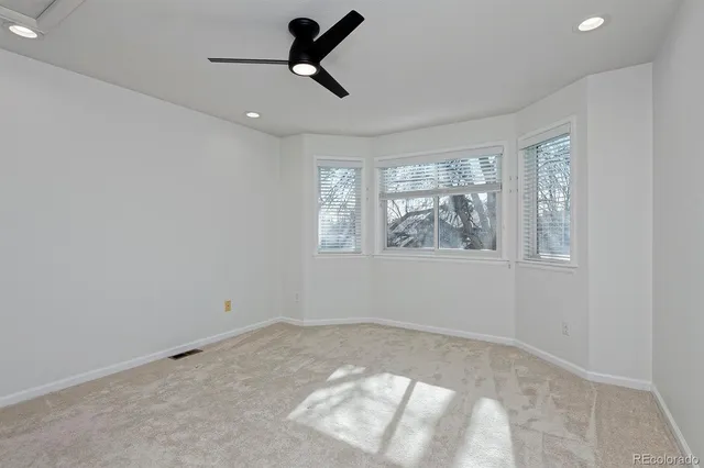 a view of empty room with window and ceiling fan