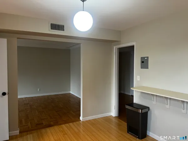 an empty room with wooden floor sink and cabinet
