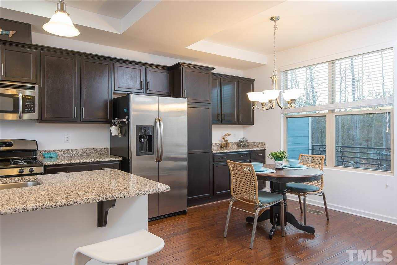 1607 Crafton Way Raleigh, NC 27607 - Photo 8 of 17 a kitchen with stainless steel appliances granite countertop a stove refrigerator a dining table and chairs with wooden floor