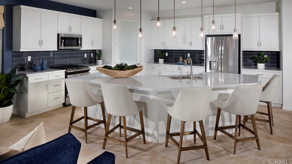 32034 Sedge Way Temecula, CA 92591 - Photo 5 of 14 a kitchen with stainless steel appliances kitchen island granite countertop a table chairs microwave and sink