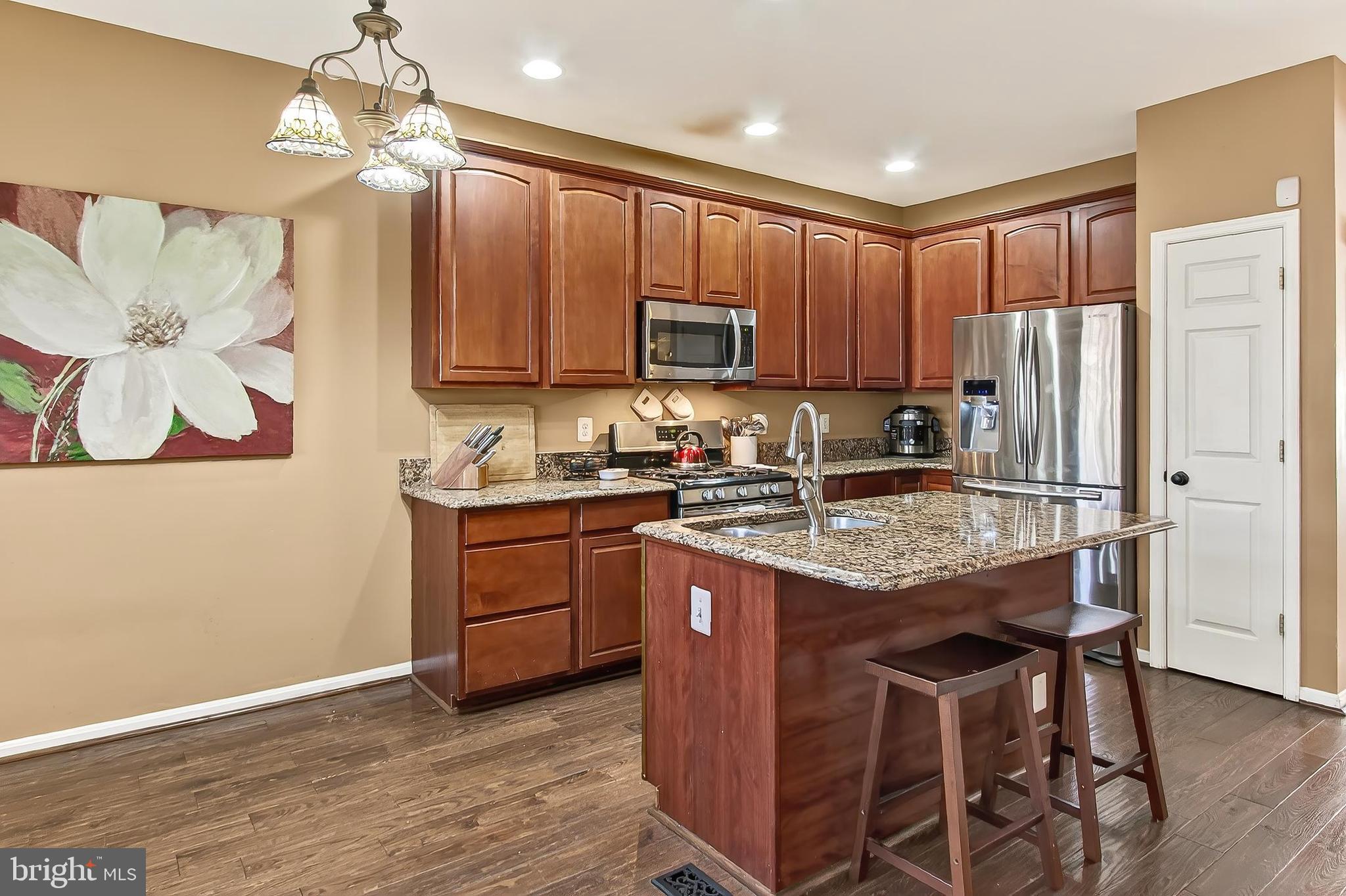 8445 Carmela Circle Springfield, VA 22153 - Photo 30 of 53 a kitchen with granite countertop wooden cabinets and a refrigerator