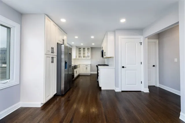 a view of a hallway with wooden floor and a kitchen