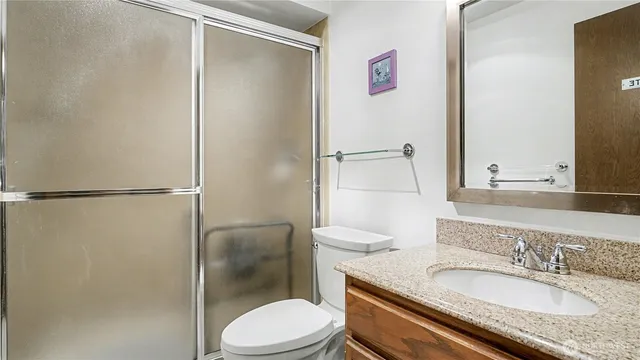 a bathroom with a granite countertop sink toilet and shower