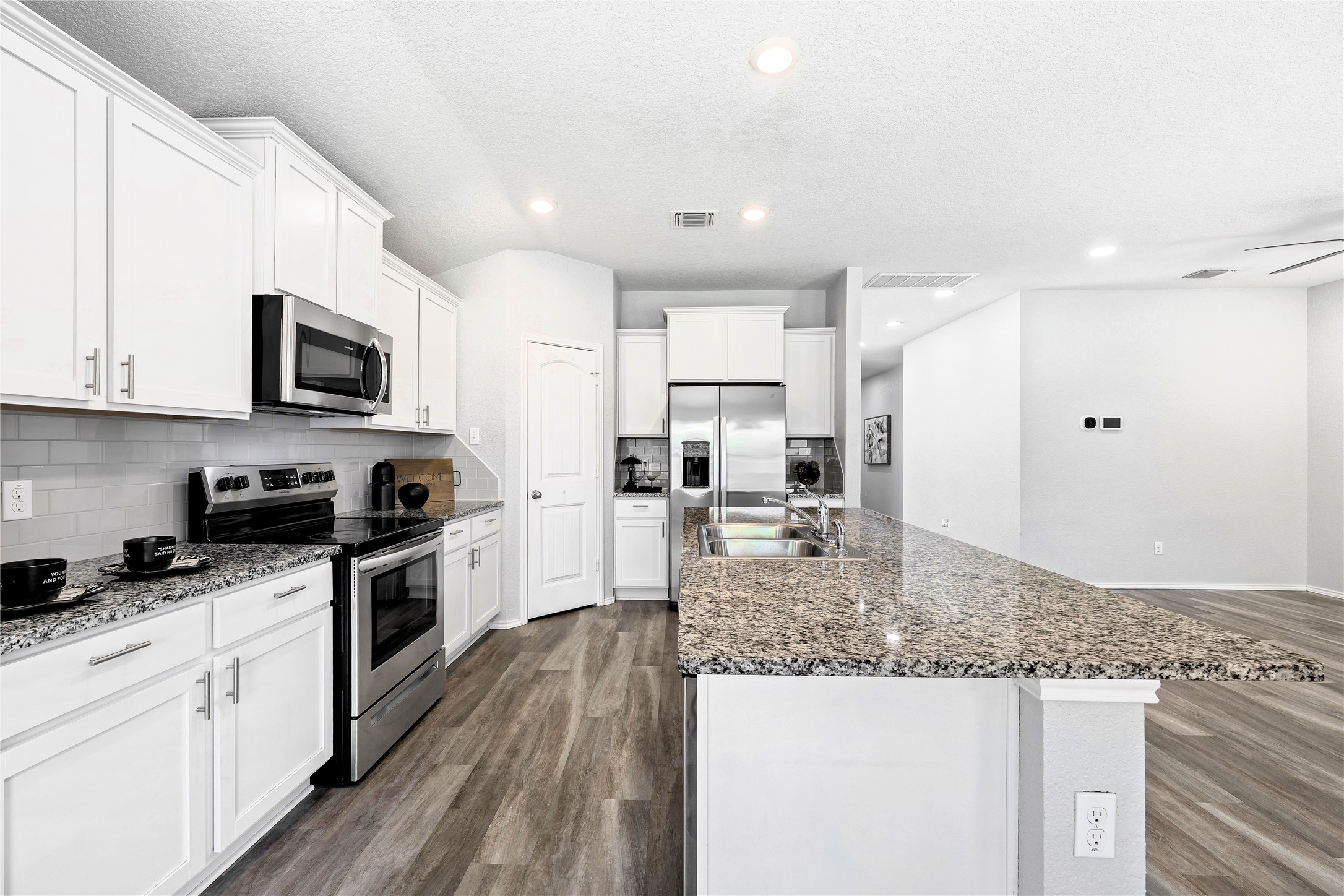 133 Beth Ann Loop Taylor, TX 76574 - Photo 11 of 30 Kitchen featuring stainless steel appliances, dark engineering flooring white cabinetry, backsplash, and recessed lighting