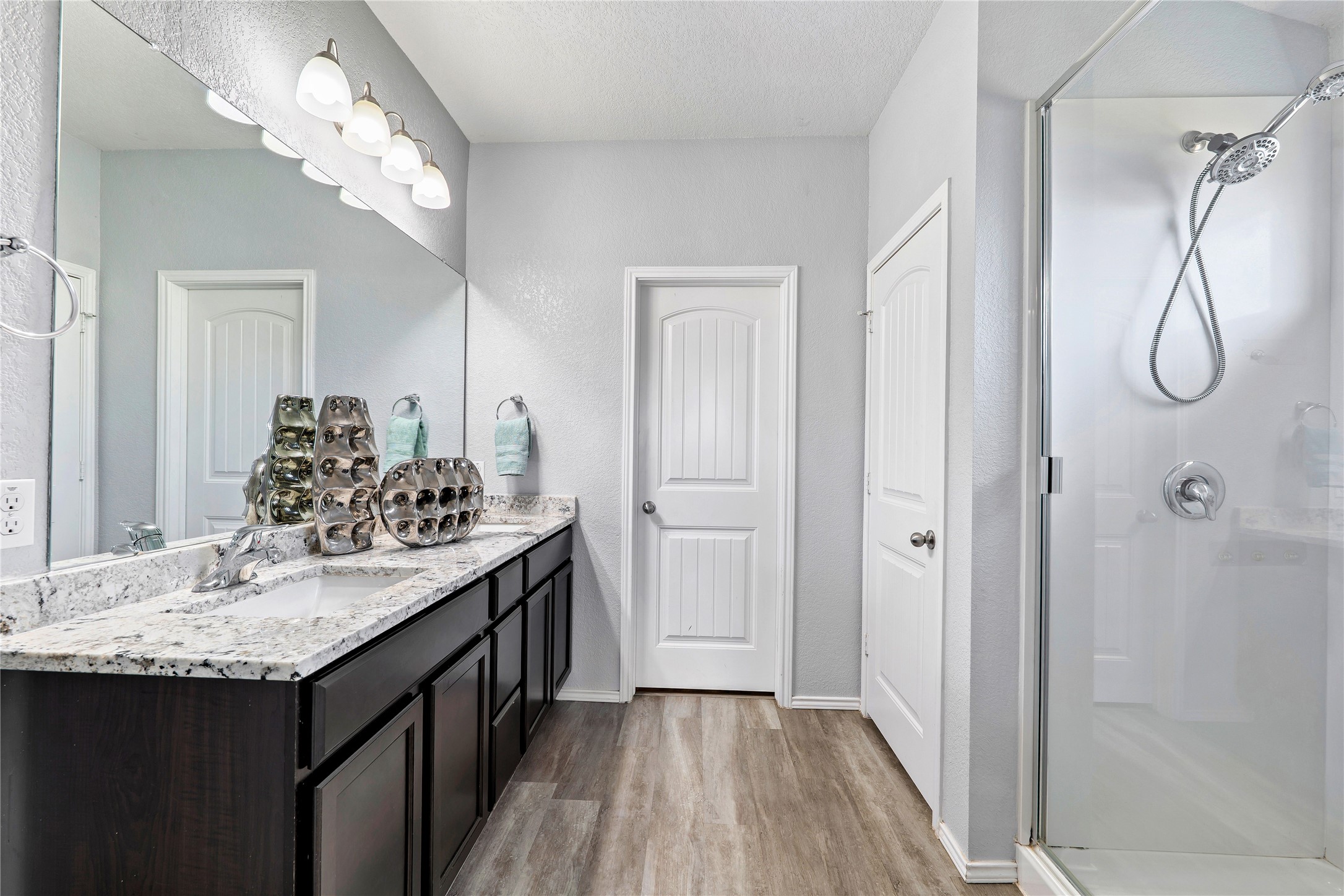 133 Beth Ann Loop Taylor, TX 76574 - Photo 17 of 30 Full bathroom with double vanity, a stall shower, light dark engineering flooring a textured ceiling, and a textured wall